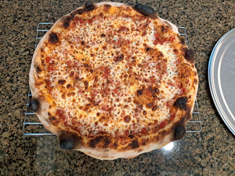 NY style cheese pizza sitting on a cooling rack