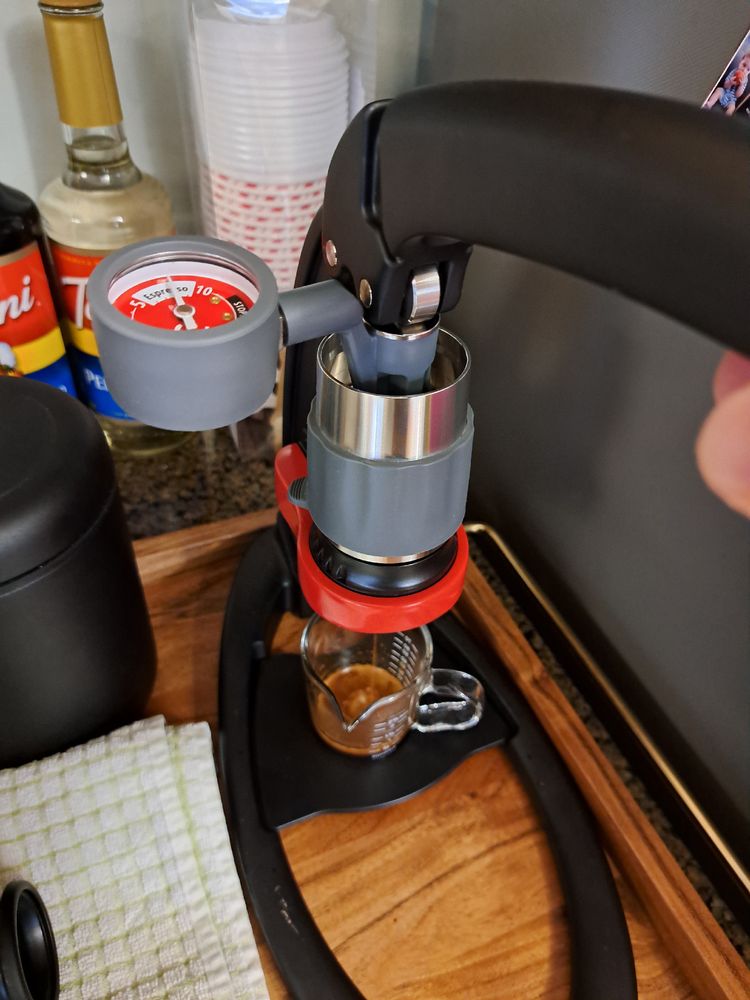 A picture of my manual espresso machine being used. A cup is partially full of espresso. A pressure gauge reads about 7.5 bar.