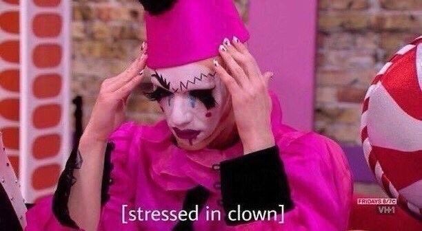 A person dressed in a bright pink and black clown costume and make up is touching their fingertips to their temples and looking down. The caption reads [stressed in clown]
