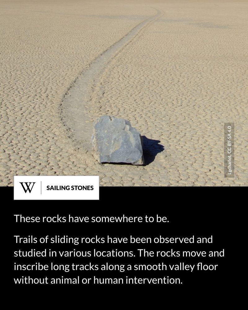 A large rock sits on cracked desert ground, leaving a long curved trail behind it. Text says: These rocks have somewhere to be. Trails of sliding rocks have been observed and studied in various locations. The rocks move and inscribe long tracks along a smooth valley floor without animal or human intervention.