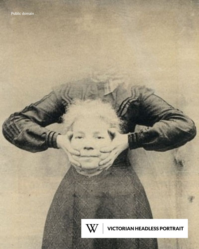 A Victorian-style photograph of a woman holding her own decapitated head in her hands at waist level, while her neck appears empty.