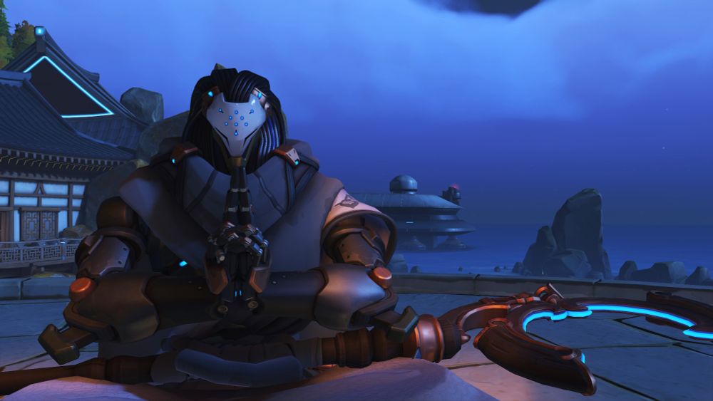 Ramattra, wearing his Travelling Monk skin and sitting out near the coast of Busan Sanctuary. His legs are crossed with his staff positioned in his lap. His hands are neatly pressed together doing some kind of focus or prayer thing I'm not really sure what it is but it's neat! 