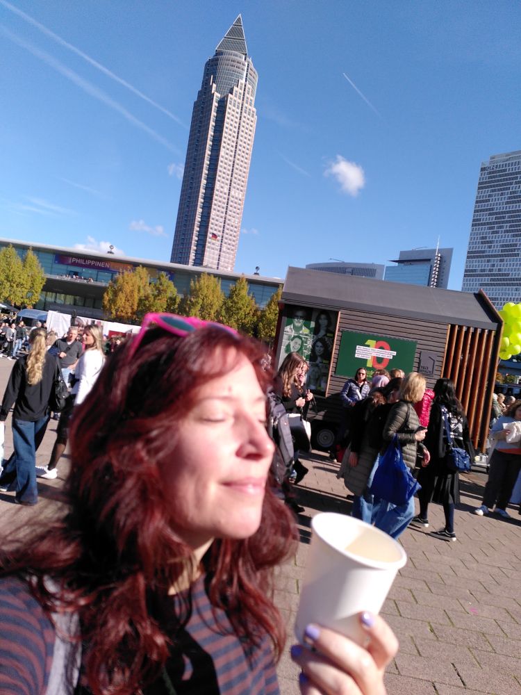 Fee mit einem Pappbecher Kaffee in der Hand vor der Frankfurter Skyline.