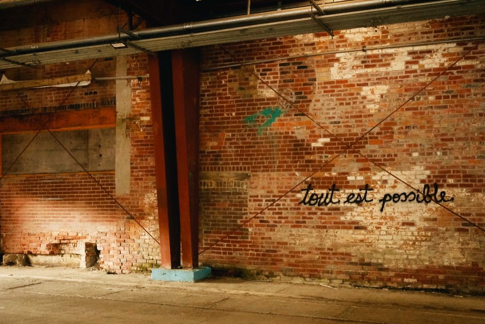An old brick wall features the spray-painted phrase “tout est possible.” 