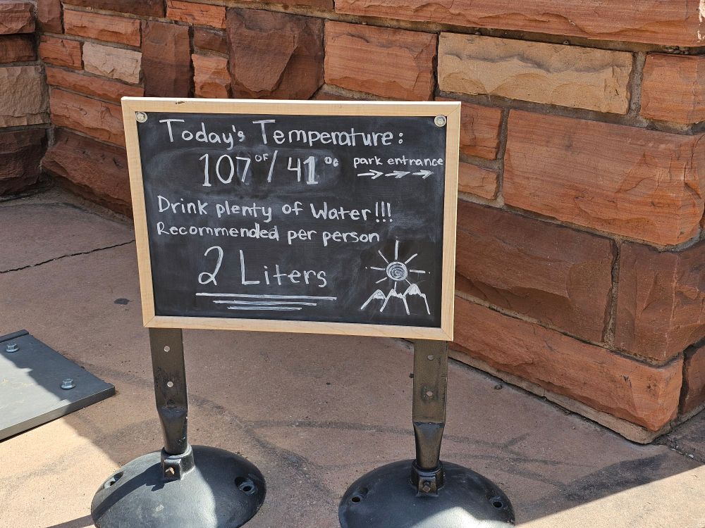 A sign outside Zion National Park with high temperatures. The high is 107 degrees F/ 41 degrees C. Visitors are recommended to drink at least 2 litres of water each