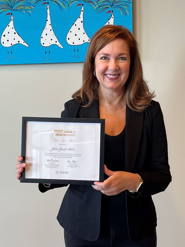 Dr. Jodie Guest holding a framed award certificate