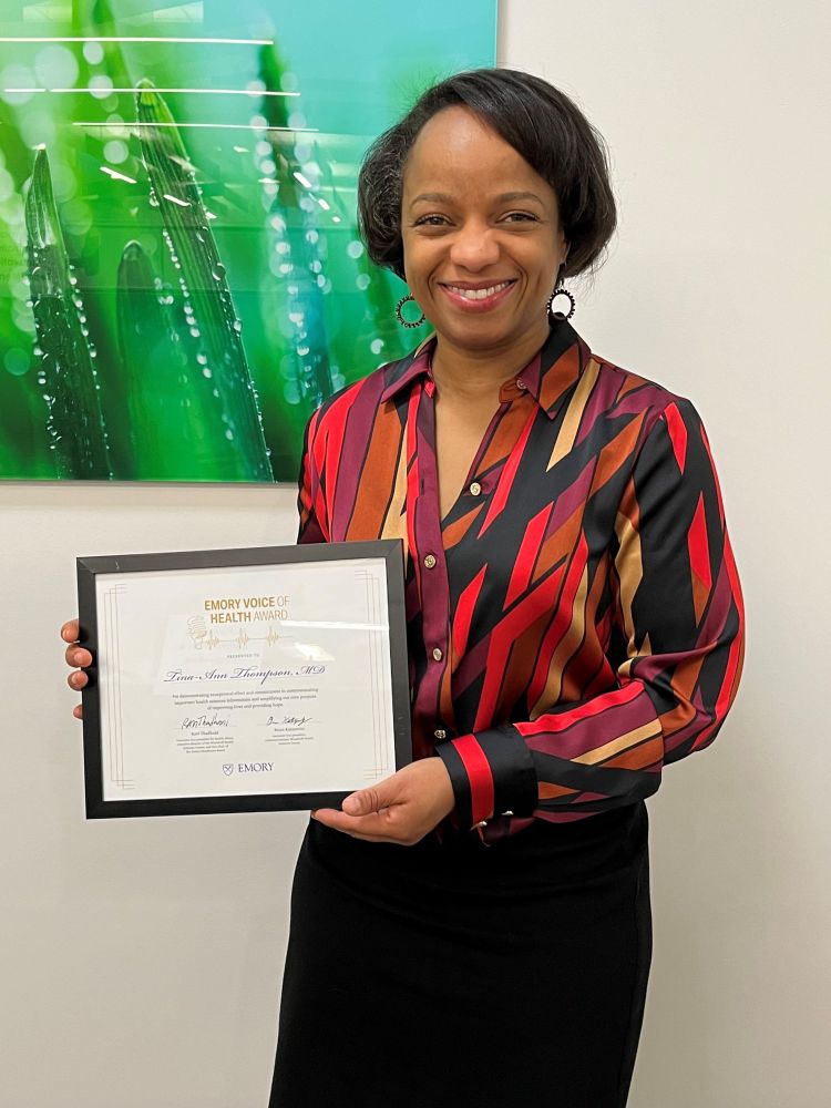 Dt. Tina-Ann Thompson holding a framed award certificate