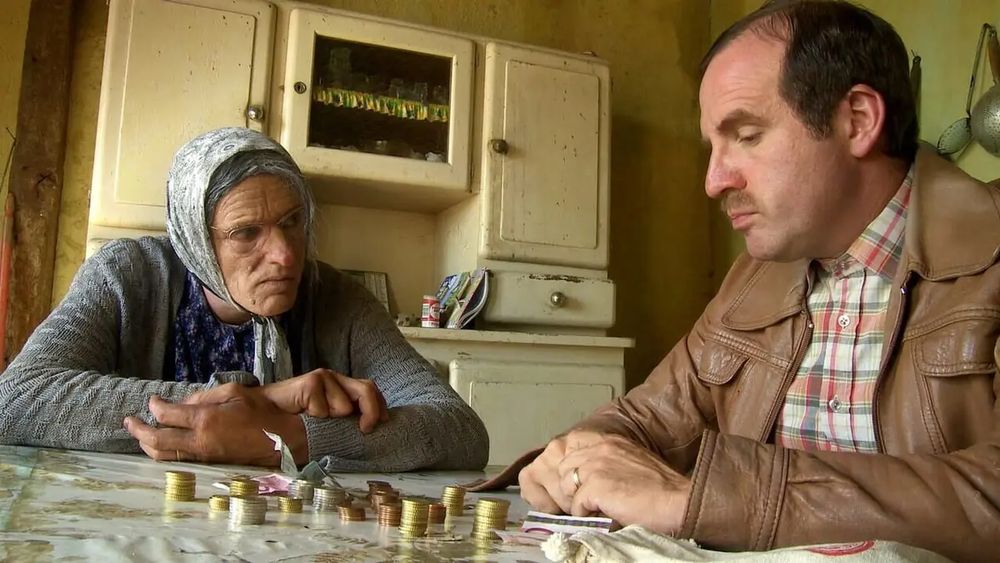 Le film Amélie au pays des Bodin's avec Maria et Christian Bodin assis sur une table avec pleins de pièces en euros empilées et des billets