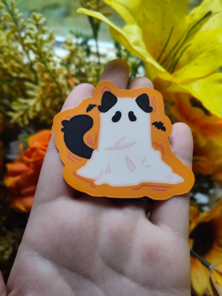 Sticker with a black cat in a white sheet ghost costume, with an orange background 
