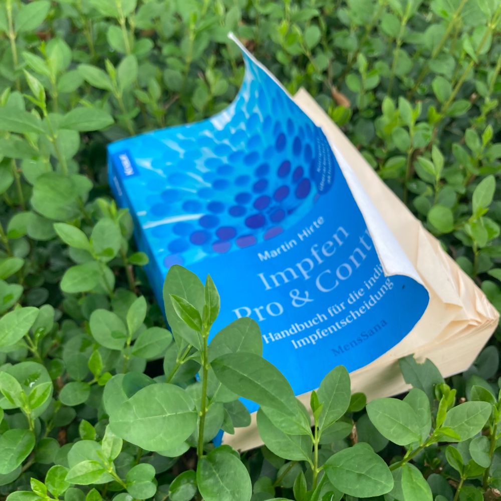 Buch "Impfen: Pro und Contra" liegt in einem Gebüsch