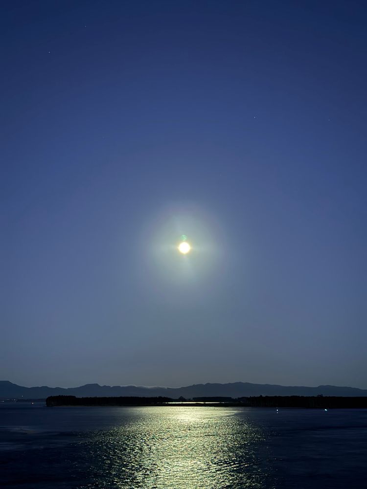A picture of the full moon with its reflection on the water taken before sunrise. 