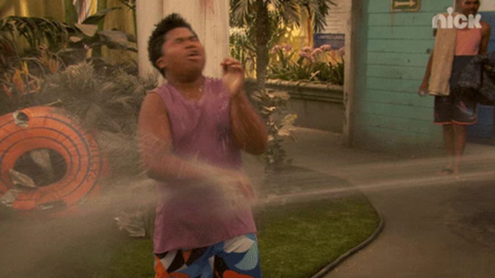 a man in a purple tank top is sprayed by a hose with the nick logo visible