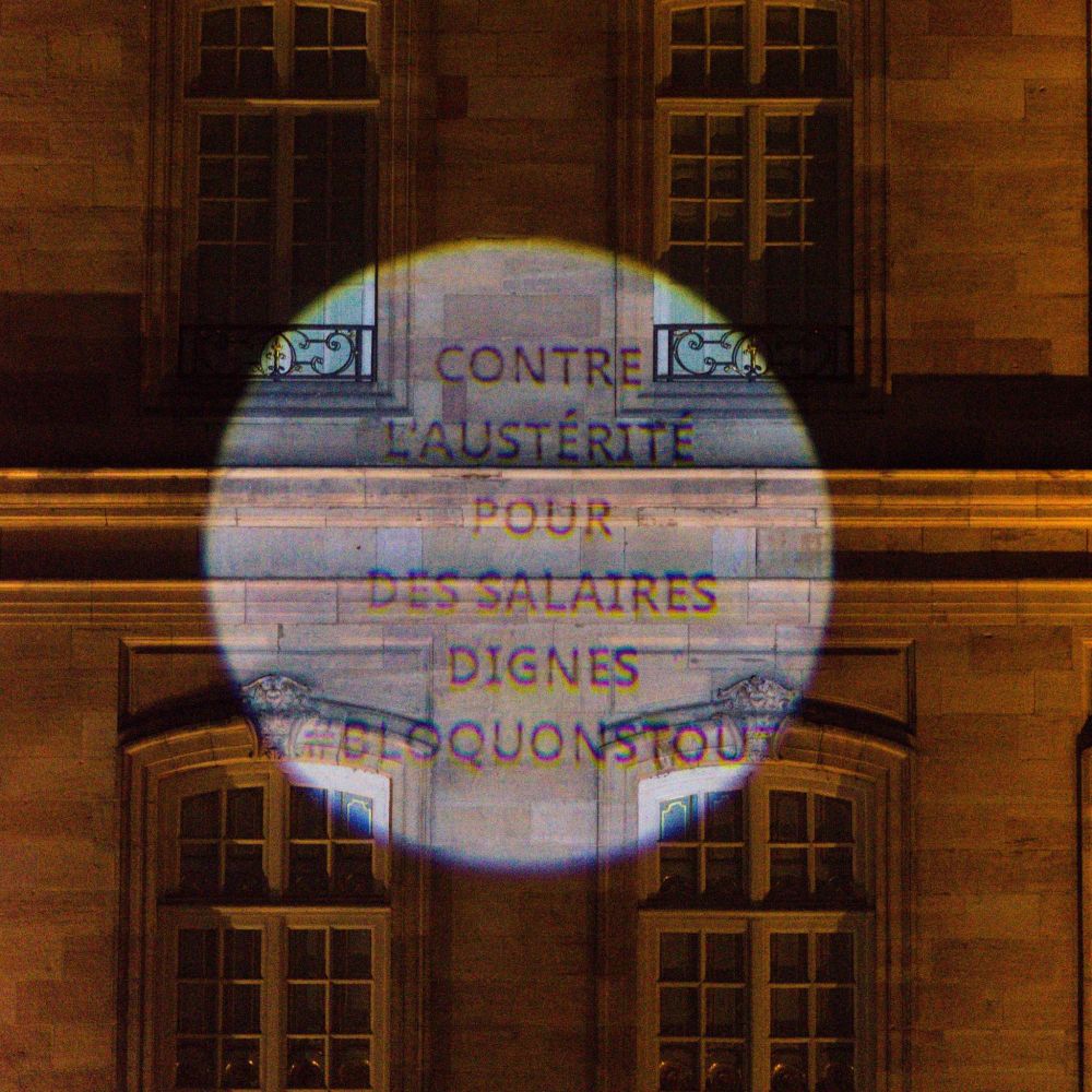 Message projeté sur un mur : Contre l'austérité, pour des salaires dignes #bloquonstout