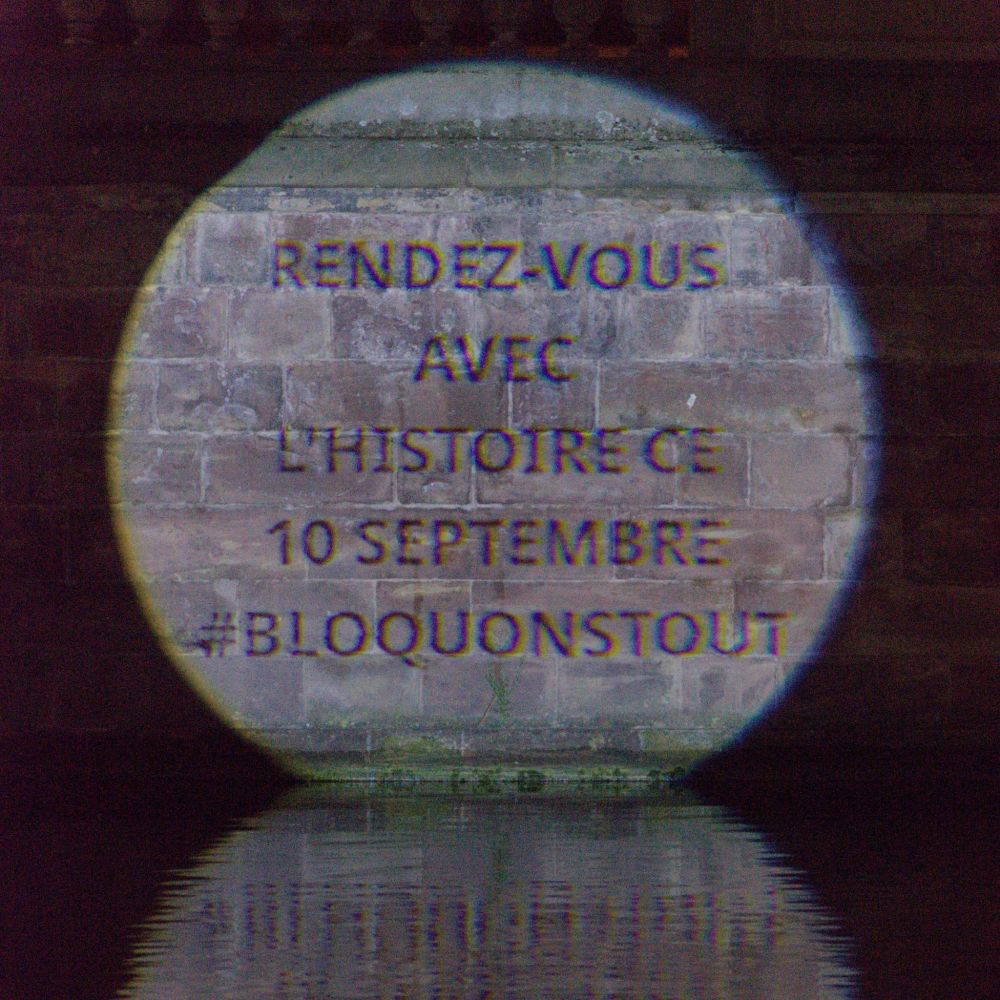 Message projeté sur un mur : Rendez-vous avec l'Histoire ce 10 septembre #bloquonstout
