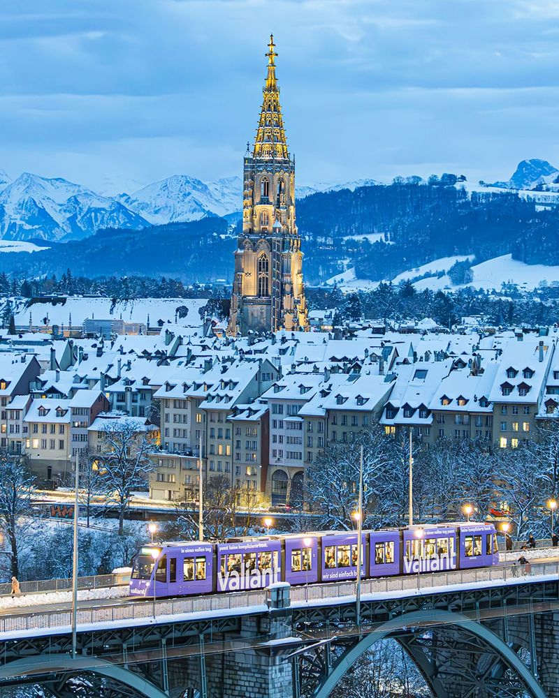 Das Werbetram der Valiant Bank fährt zur blauen Stunde über die Kornhausbrücke in Bern. Im Hintergrund sind die verschneite Altstadt, das beleuchtete Münster und die Berner Alpen zu sehen. 