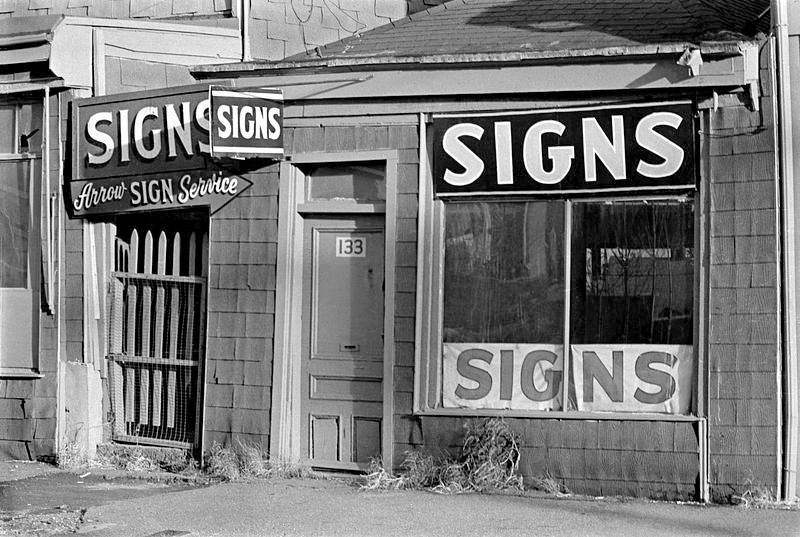 Storefront with four signs saying Signs, or Arrow Sign Services