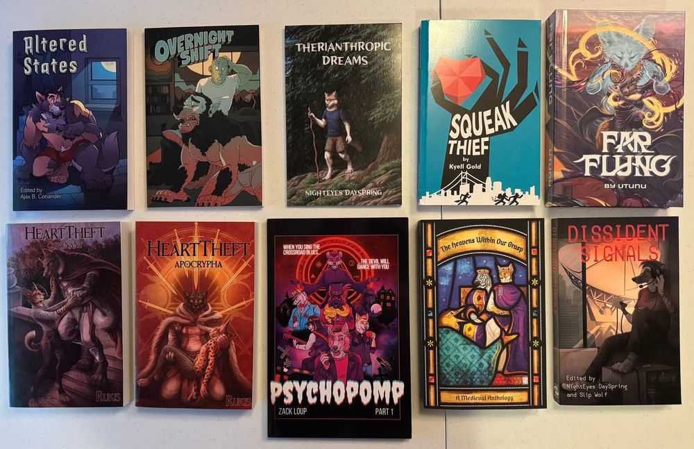 A collection of ten books on a table. From top left, moving clockwise, they are titled "Altered States," "Overnight Shift," "Therianthropic Dreams," "Squeak Thief", "Far Flung," "Dissident Signals," "The Heavens Within Our Grasp," "Psychopomp," "HeartTheft Apocrypha", and "HeartTheft Covenant."