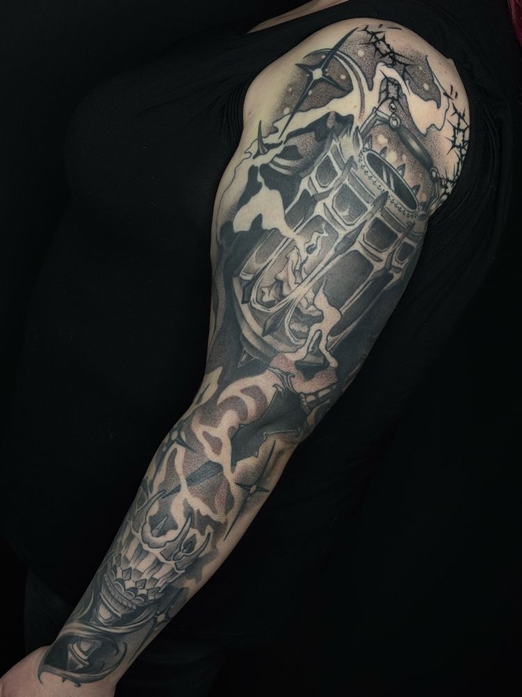 A completed half sleeve tattoo in all black ink on pale skin. The tattoo weaves together several gothic motifs: a medieval aesthetic iron torch, a dagger with a black blade, and a wrought-iron lantern. Smoke, fire, and darkness weave the design together, with stylized stars scattered throughout. 