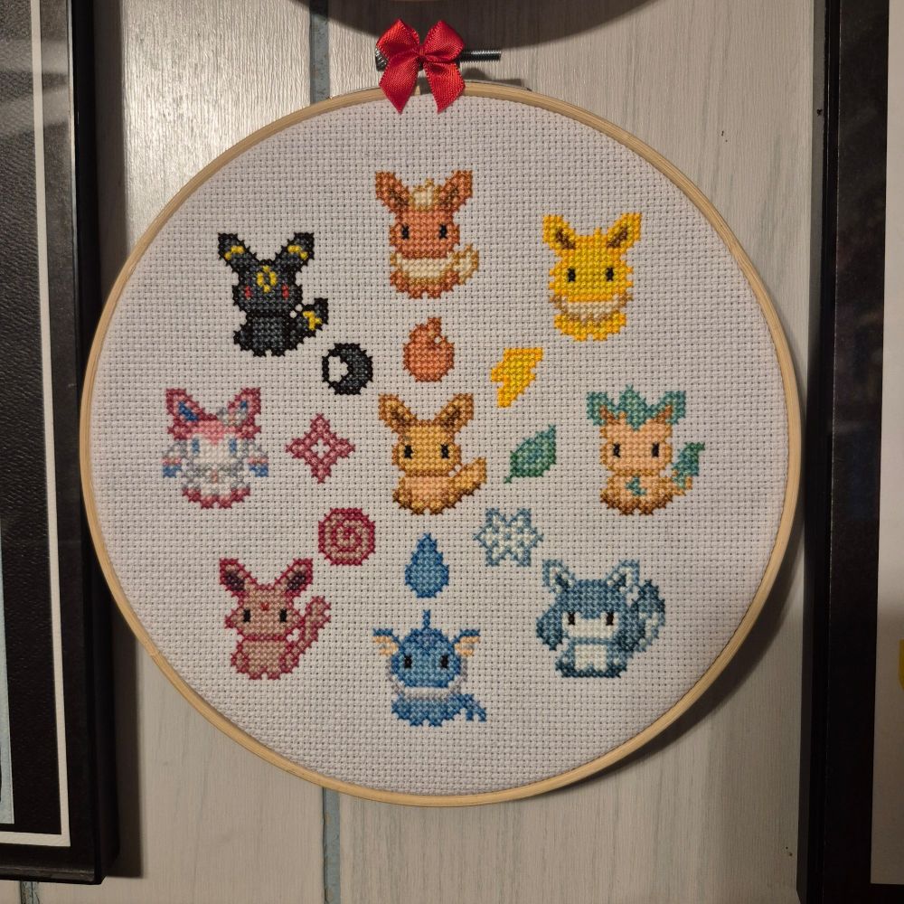 A finished cross stitch of eevee and its evolutions surrounding it