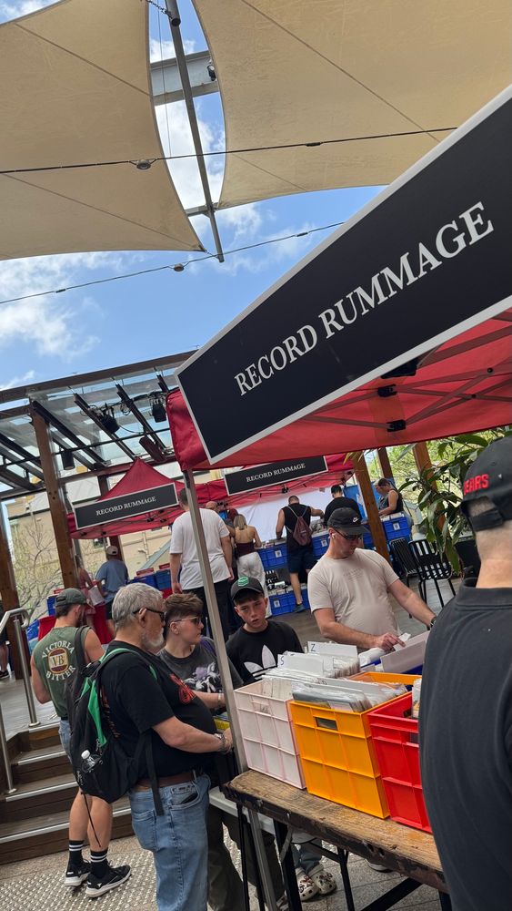 Some red market stalls with RECORD RUMMAGE signs and milk crates of records. 