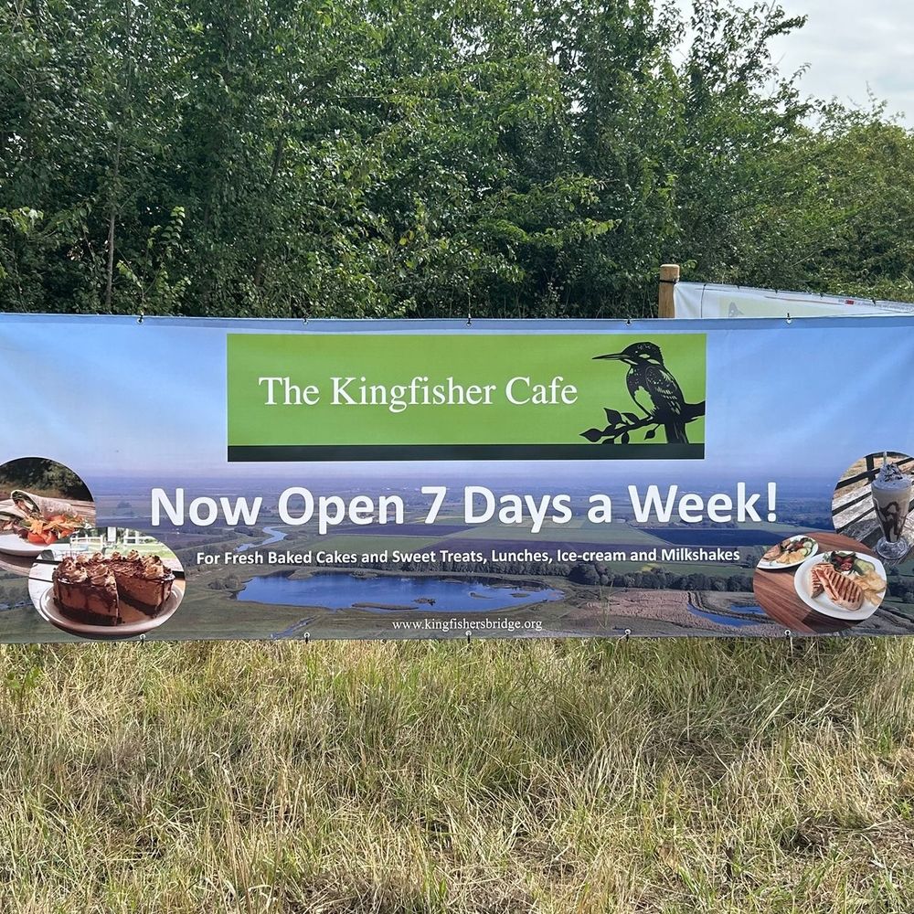 Banner for the Kingfisher Cafe, reading "Now Open 7 Days a Week! For fresh baked cakes and sweet treats, lunches, ice-cream and milkshakes" www.kingfishersbridge.org