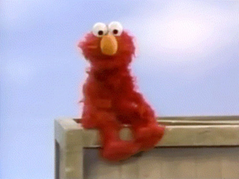 elmo is sitting on a box and looking up at the sky