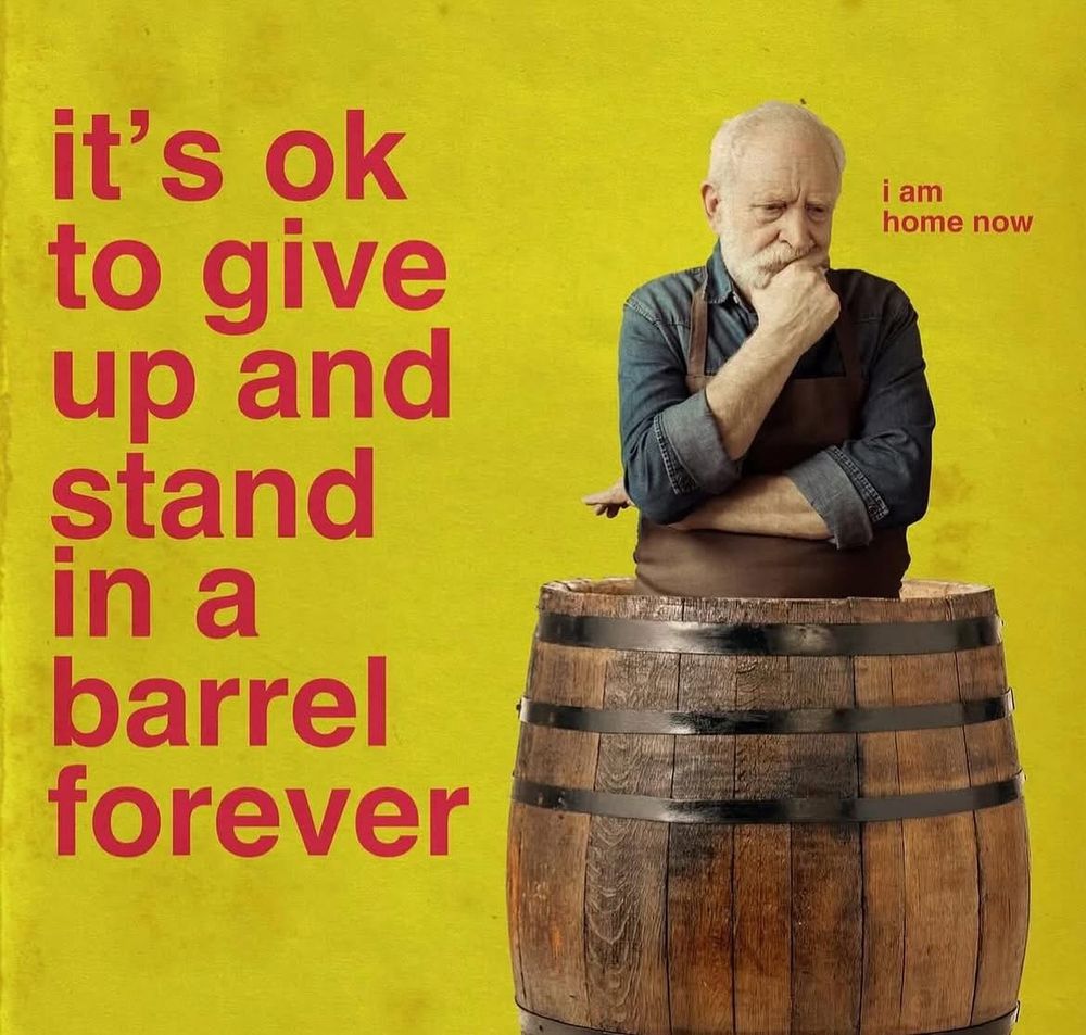 A man standing in a barrel with text next to him saying it’s OK to give up and stand in a barrel forever. “I am home now,” thinks the man.