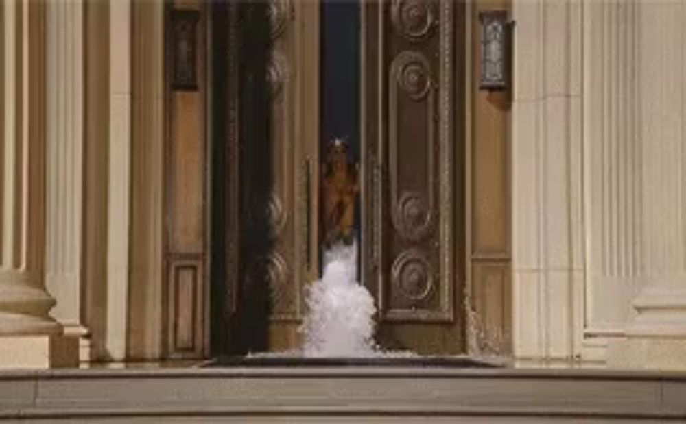 a person is standing in front of a door that is open and a fountain is coming out of it .