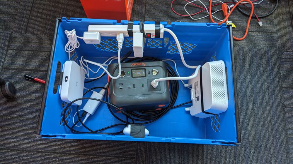 A blue tote with a jackery power supply, a power strip, a unifi gateway, a WiFi AP and a 5G router all taped inside.