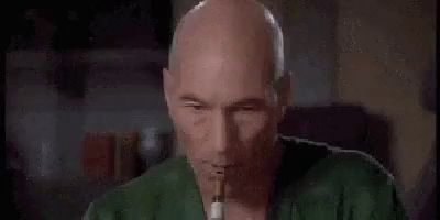 a bald man is smoking a cigarette while holding a cigarette in his mouth .