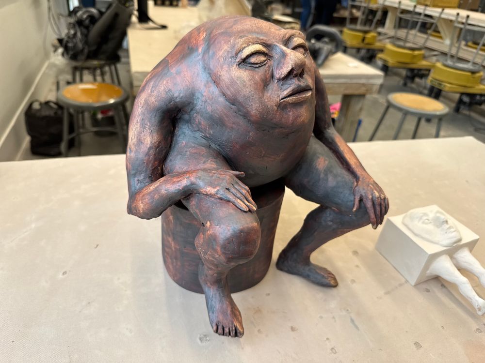 seated ceramic sculpture with an iron oxide wash