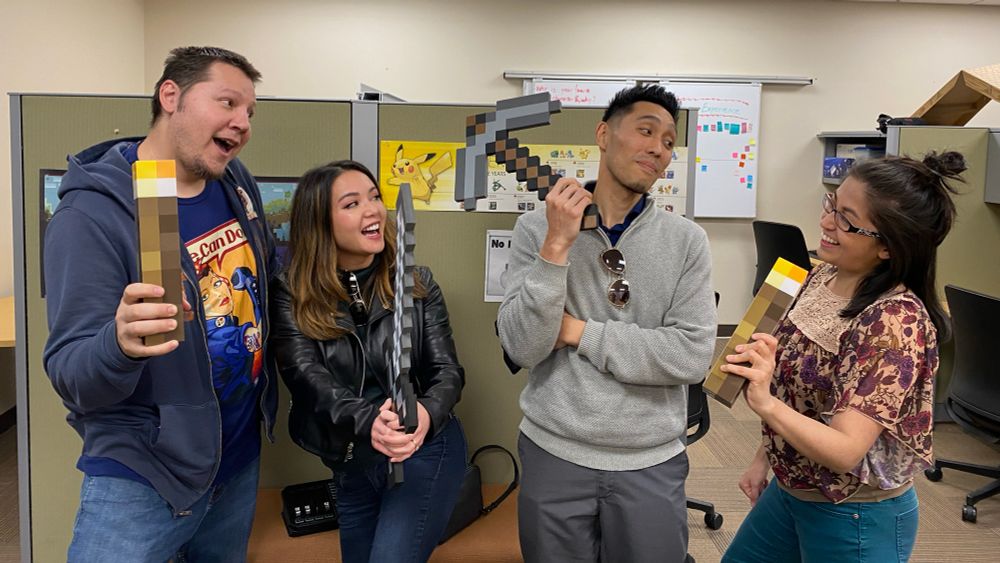 Four friends hold 3D-printed Minecraft items while standing in an office