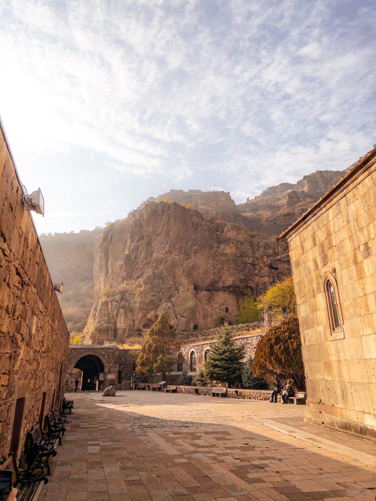 View from inside a courtyard in orange glow, framing a nearby cliff