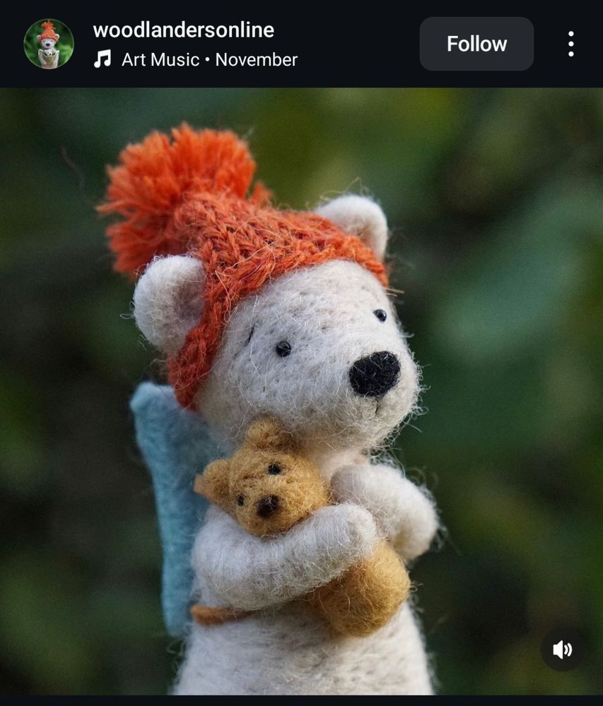 Needle felted bear in an orange bobble hat. Bear is hugging a tiny teddy bear
