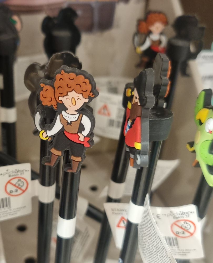 A pen with a pirate lady on top. The pirate has long curly brown hair tied on a pony tail and she is holding a cutlass and smiling