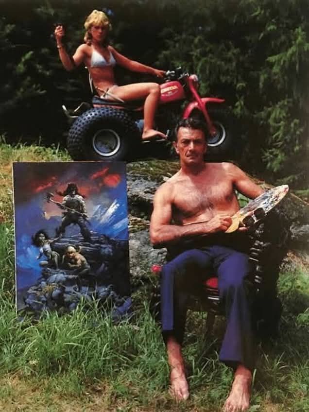 See post. It's Frazetta in a chair with an easel. His shirt is off.

His daughter, Heidi, is behind him wearing a bikini and sitting on a three wheeler. 