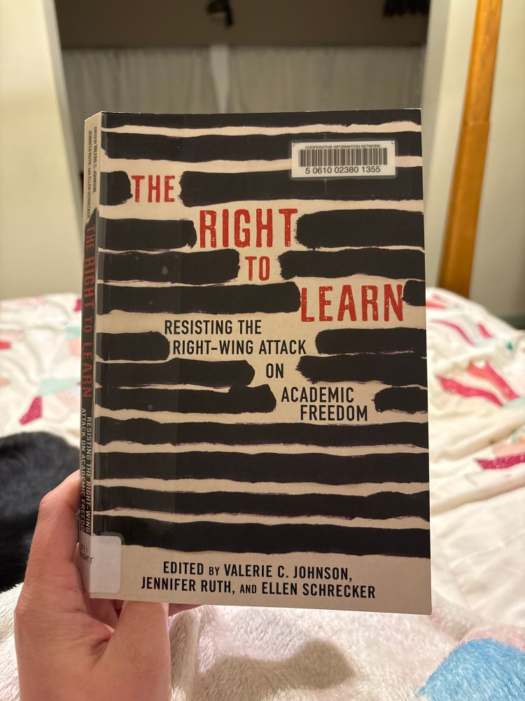 A copy of “The Right to Learn: Resisting the Right-Wing Attack on Academic Freedom” edited by Valerie C. Johnson, Jennifer Ruth, and Ellen Schrecker. The book is being held up and obscuring the view of a quilted bedspread in the background. 