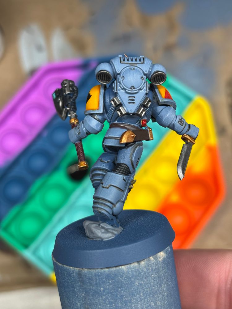 Space Wolf mini painted in front of a rainbow paint pallet that’s also a fidget.
