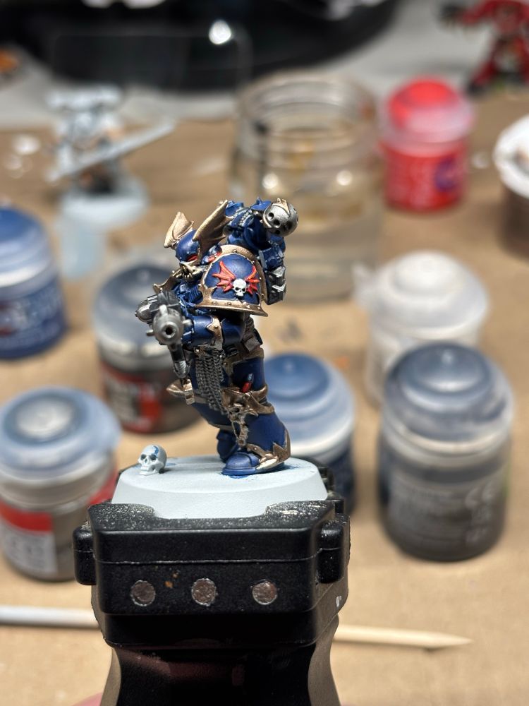 Painted nightlord mini on a mini holder with paints in the background.
