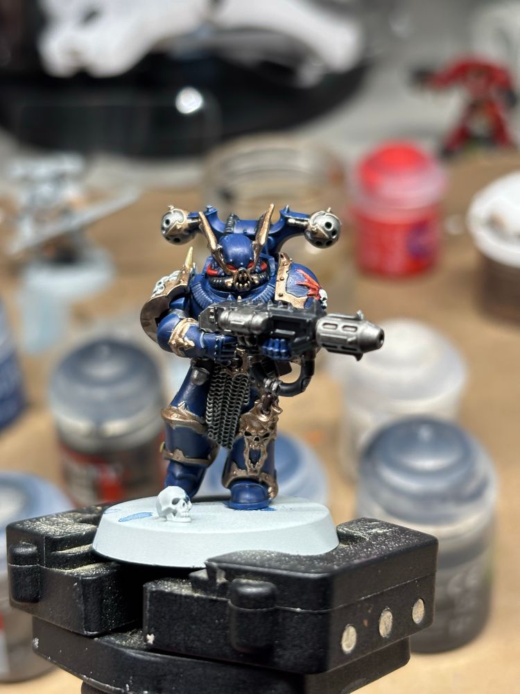 Painted nightlord mini on a mini holder with paints in the background.