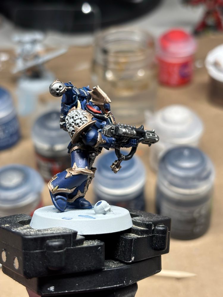 Painted nightlord mini on a mini holder with paints in the background.