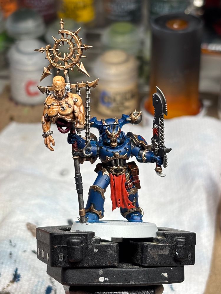 Nightlord Ventrilokar painted mini with paint in the background. 