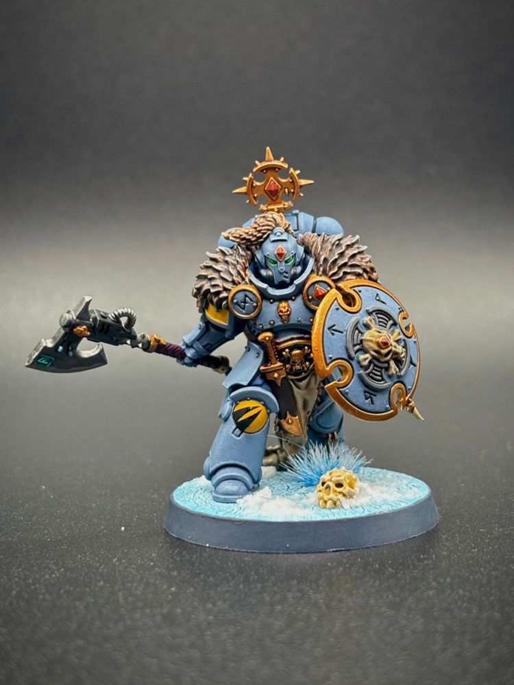 Helmeted Space Wolf head taker with axe and shield on black background.