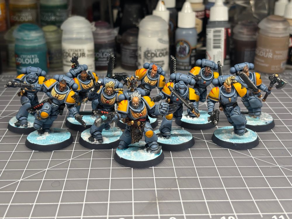 Painted Space wolf blood claw minis on a painting workspace in front of a bunch of paint. 