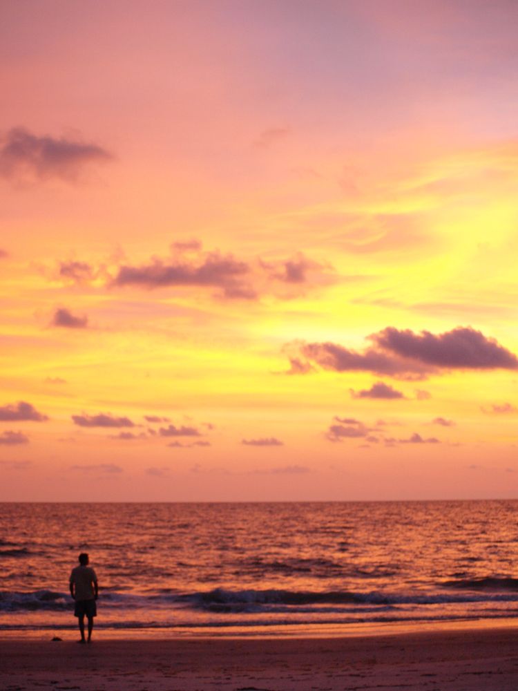 The setting sun turns the sky golden yellow with hints of lavender and pink, turning the sea to copper and staining the sand dark purple as a man (me) stands in awe.
