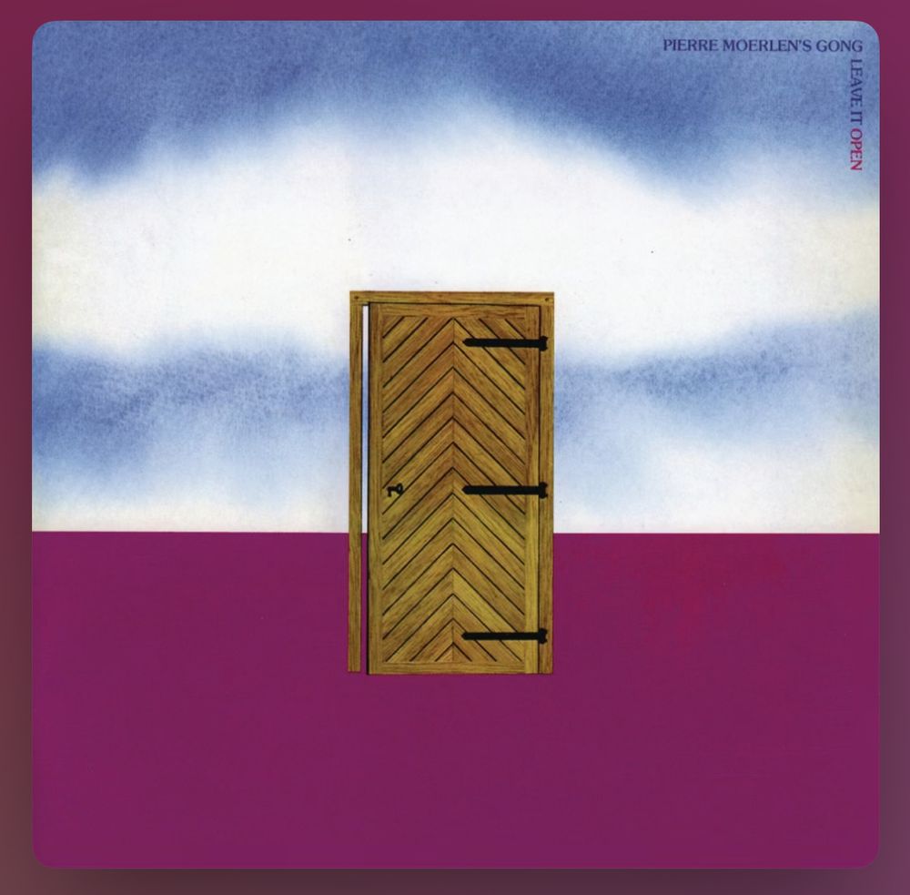 Album cover for Pierre Moerlen’s Gong, Leave It Open. It shows purple foreground with sky and clouds above and a herringbone-pattern wooden door in the centre, slightly ajar. 