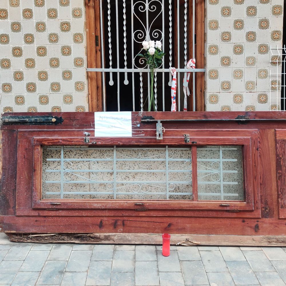 flors blanques i una espelma en la finestra d'una casa de Paiporta 