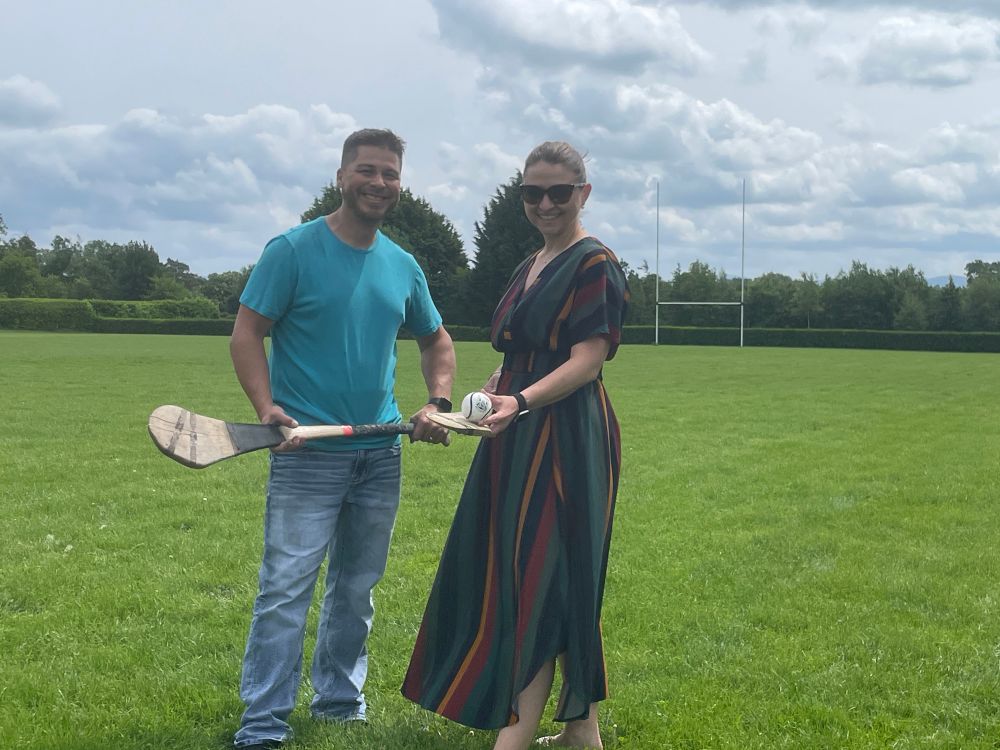 Two people on a Hurling pitch with hurleys and sliotar