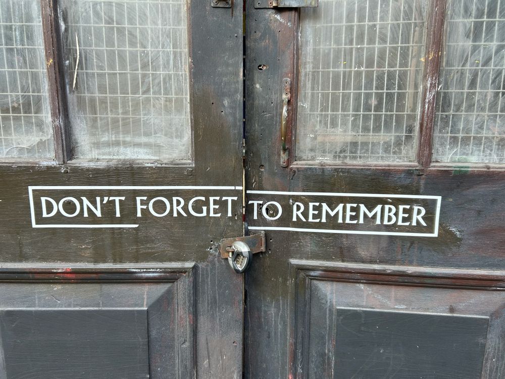 Old blue-painted doors with a padlock and painted sign that says “don’t forget to remember”