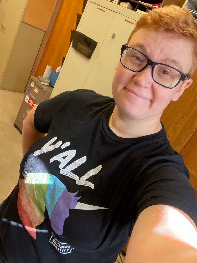 Lis in a rainbow unicorn y’all shirt
